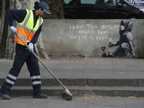 A road worker passes by an artwork which appears to be by street artist Banksy which has appeared near the former location of the Extinction Rebellion camp in Marble Arch, London, Friday April 26, 2019.