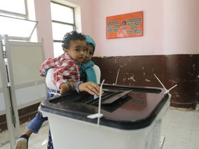 A voters carries her son as she casts her ballot on constitutional amendments during the first day of three-day voting at polling station in Cairo, Egypt, Saturday, April 20, 2019. Egyptians are voting on constitutional amendments that would allow el-Sissi to stay in power until 2030.