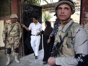 A policeman assists a voter as she leaves a polling station in Cairo.