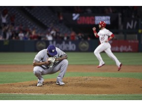 Milwaukee Brewers starting pitcher Freddy Peralta squats on the mound after giving up a three-run home run to Los Angeles Angels' Tommy La Stella during the first inning of a baseball game Tuesday, April 9, 2019, in Anaheim, Calif. In the background is Angels' Jonathan Lucroy.