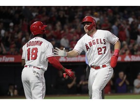 Los Angeles Angels' Mike Trout, right, is greeted by Brian Goodwin after he scored on a single by Albert Pujols during the first inning of a baseball game against the Milwaukee Brewers, Tuesday, April 9, 2019, in Anaheim, Calif.