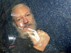 Julian Assange gestures as he arrives at Westminster Magistrates' Court in London after he was arrested by the Metropolitan Police and taken into custody Thursday April 11, 2019.