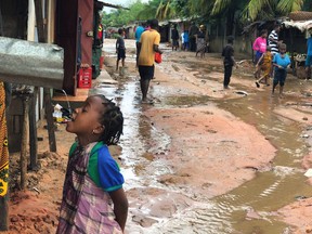 A child drinks water from a gutter during floods due to heavy rains in Pemba, Mozambique.