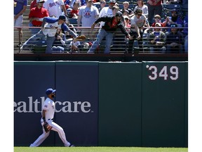 Texas Rangers right fielder Nomar Mazara watches a fans reach out for a Oakland Athletics' Khris Davis double in the first inning of a baseball game in Arlington, Texas, Sunday, April 14, 2019.