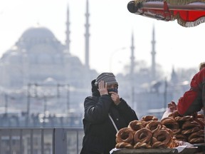 In this Thursday, April 4, 2019 photo, a woman, backdropped by the Suleymaniye mosque, buys simit, a pretzel-like snack, in Istanbul. The mood among opposition supporters in Turkey's biggest city is one of jubilation but also worry - fear that their win in Istanbul's mayoral race could be overturned in a recount taking place after the ruling party challenged the election results.