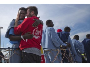 FILE - In this Sunday, Feb. 5, 2017 file photo, Kybumba Fran, 25, from Cameroon, cries with the head of the mission of Proactive Open Arms NGO Riccardo Gatti, from Italy, as he leaves the Golfo Azzurro rescue vessel after arriving at the port of Pozzallo, south of Sicily, Italy, with more than 220 migrants aboard the ship rescued at the Mediterranean sea. Spanish aid groups say Spain is allowing them to deliver aid supplies to refugee camps in Greek islands, but they face hefty fines if their boats venture into official search and rescue areas in the Central Mediterranean.