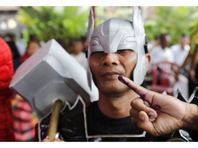 A man in Thor's costume shows his inked finger after casting at a polling station during election in Bali, Indonesia on Wednesday, April 17, 2019. Voting is underway in Indonesia's presidential and legislative elections after a campaign that that pitted the moderate incumbent against an ultra-nationalist former general.