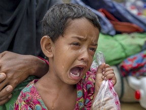 FILE- In this Oct. 20, 2017, file photo, Rohingya Muslim girl Toyiba Khatun cries while fighting fever as she waits with her family to be registered which will then allow them to proceed to build a shelter in Kutupalong refugee camp, Bangladesh. A new report by the United Nations children's agency says the lives and futures of more than 19 million Bangladeshi children are at risk from colossal impacts of devastating floods, cyclones and other environmental disasters linked to climate change. The UNICEF report released Friday, April 5, 2019, said the tally includes Rohingya refugee children from Myanmar who are living in squalid camps in southern Bangladesh.