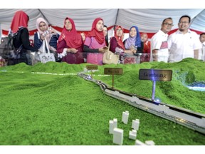 In this Sept. 8, 2017, photo, visitors view a scale model of the ECRL (East Coast Rail Link) during the launching of the train project in Kuantan, east coast of peninsula Malaysia. Malaysia's government says it has decided to resume a China-backed rail link project after the Chinese contractor agreed to cut construction cost by one-third. (AP Photo)