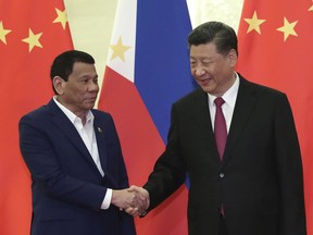 FILE - In this April 25, 2019, file photo, Philippine President Rodrigo Duterte, left, shakes hands with Chinese President Xi Jinping, right, before their meeting at the Great Hall of People in Beijing. Duterte raised his nation's concerns over territorial disputes in the South China Sea at a meeting with Chinese President Xi Jinping in Beijing that followed the signing of multi-billion dollar trade agreements.