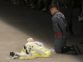 Model Tales Soares lies on the catwalk as a paramedic tends to him after he collapsed during Sao Paulo Fashion Week in Sao Paulo, Brazil, Saturday, April 27, 2019.