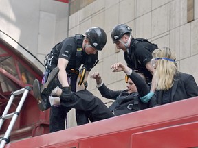 Police begin to remove climate activists who glued themselves on top of a Dockland Light Railway train at Canary Wharf station in east London as part of the ongoing climate change protests in the capital on Wednesday April 17, 2019.