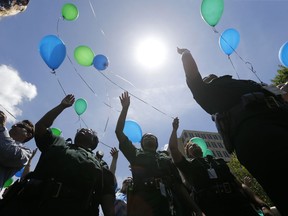 FILE - In this July 20, 2106 file photo, East Baton Rouge Sheriff's deputies release balloons at a noon vigil organized by municipal court workers in downtown Baton Rouge, La., in honor of slain and injured sheriff deputies and police. Bills are pending in a growing number of states in 2019 to ban the feel-good tradition of releasing helium-filled balloons at events, since they have the unintended consequence of spoiling the environment and threatening wildlife.