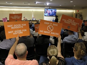 People opposed to a proposed homeless shelter hold up signs during a meeting of the Port Commission Tuesday, April 23, 2019, in San Francisco. San Francisco port commissioners will vote on whether to approve or reject a proposal to put a temporary homeless shelter along the Embarcadero.