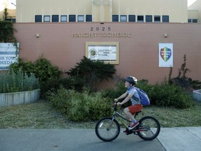 In this Thursday, April 25, 2019 photo, a student arrives for a day of classes at Haight Elementary School on a bicycle in Alameda, Calif. School district officials are changing the name of the school to Love Elementary after it was discovered that former California Governor Henry H. Haight had racist tendencies.