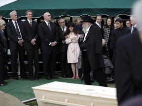 Hannah Kaye, the daughter of shooting victim Lori Kaye, center, holds the hand of her father, Howard Kaye, as Rabbi Yisroel Goldstein speaks during funeral services, Monday, April 29, 2019, in San Diego. Lori Kaye was killed when a man opened fire two days earlier inside a synagogue near San Diego, as worshippers celebrated the last day of a major Jewish holiday.