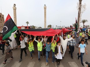 FILE - In this Friday, April 26, 2019, file, photo, protesters march against military operations by Field Marshal Khalifa Hifter's forces in Martyrs' Square on in Tripoli, Libya. Libyan forces loyal to a former military commander have intensified their airstrikes on Tripoli, where heavy fighting and blocked roads have left civilians trapped in their homes, officials said Monday.
