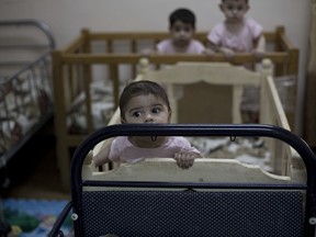 FILE - In this Aug. 15, 2018 file, photo, baby girls stand up in their cribs at Salhiya Orphanage, which now hosts foreign and Iraqi children of Islamic State militants, in Baghdad, Iraq. The spiritual council for Iraq's Yazidi community said Sunday, April 28, 2019, that it will not embrace the children of women raped by Islamic State group men, just days after it said it would accept "all survivors" of the extremist group's attempted annihilation of the minority community.