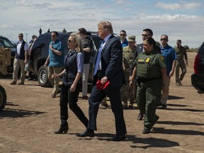 President Donald Trump walks with Homeland Security Secretary Kirstjen Nielsen as they visit a newly constructed part of a border wall with Mexico.