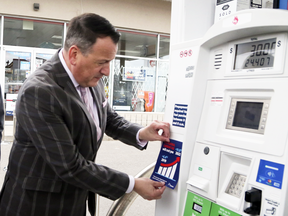 Ontario Energy Minster Greg Rickford attaches a carbon tax sticker on a gas pump during a press conference, April 8, 2019.