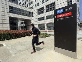 A runner passes the Ronald Reagan UCLA Medical Center on the campus of the University of California, Los Angeles Friday, April 26, 2019. Some students and employees possibly exposed to measles at two Los Angeles universities were still quarantined on campus or told to stay home Friday, but the numbers were dwindling as people were able to show they were vaccinated for the highly contagious disease. The measures were ordered this week at UCLA and California State University, Los Angeles.