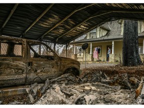 In this March 19, 2019, Sean and Dawn Herr collect an American flag that survived the Camp Fire along with their Paradise, Calif., home. The Herrs' home, built in 2010, was scorched and had smoke damage inside so the family is living indefinitely in nearby Chico. The Herrs credit the home's survival to strict building codes and to gravel that encircled the building and kept the flames back.