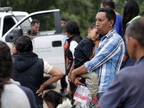 FILE - In this March 14, 2019, file photo, families who crossed the nearby U.S.-Mexico border near McAllen, Texas, wait for agents to check names and documents. The Trump administration has cut back on family detention even as it complains it has to "catch and release" migrant families, many of them Central American parents and children who seek asylum.