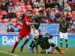 Toronto FC midfielder Jay Chapman (14) and Portland Timbers midfielder Cristhian Paredes (22) chase down a ball overtop of Portland Timbers forward Jeremy Ebobisse (17) during second half MLS soccer action at BMO field in Toronto, Saturday, April 27, 2019.