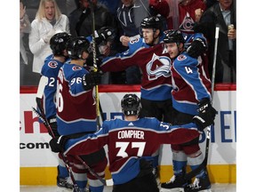 Colorado Avalanche center Nathan MacKinnon, back center, is congratulated after his power-play goal by teammates Gabriel Landeskog, back left, and Mikko Rantanen, front left, J.T. compeer, front, and Tyson Barrie in the first period of Game 3 of a first-round NHL hockey playoff series against the Calgary Flames, Monday, April 15, 2019, in Denver.