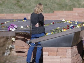 A woman looks over the stories of the slain before a vigil at the memorial for the victims of the massacre at Columbine High School nearly 20 years ago Friday, April 19, 2019, in Littleton, Colo.