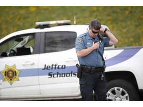 An officer from Jefferson County, Colo., Schools listens on his radio as students leave Columbine High School late Tuesday, April 16, 2019, in Littleton, Colo. Following a lockdown at Columbine High School and other Denver area schools, authorities say they are looking for a woman suspected of making threats.