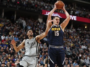 Denver Nuggets center Nikola Jokic, right, pulls in a rebound as San Antonio Spurs guard Derrick White defends in the first half of Game 7 of an NBA basketball first-round playoff series Saturday, April 27, 2019, in Denver.