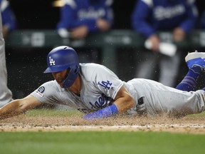 Los Angeles Dodgers' Austin Barnes scores from third base on a wild pitch thrown by Colorado Rockies reliever Carlos Estevez during the fifth inning of a baseball game Sunday, April 7, 2019, in Denver.