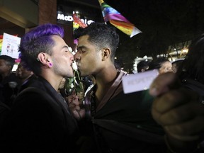 A same sex couple kiss a rose during a "Kiss-a-thon," as a form of protest for LGBT rights in Bogota, Colombia, Wednesday, April 17, 2019. The event was held at the same Andino shopping mall where days ago two gay men were harassed by a customer who lured police into fining them for "exhibitionism."