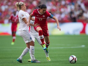Canada's Christine Sinclair, right, leaps past a challenge from England's Steph Houghton during second half FIFA Women's World Cup quarter-final soccer action in Vancouver, B.C., on Saturday June 27, 2015. Canada takes on England in  an international soccer friendly in a rematch of the 2015 Women's World Cup quarterfinal won 2-1 by England.