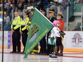 A young girl carries a Humboldt Broncos flag as she skates pass first responders during a tribute to the team after their SJHL game against the Nipawin Hawks in Humboldt, Sask., on Wednesday, Sept. 12, 2018. Families of people who died in the Humboldt Broncos bus crash say scholarships, events and places named in their honour help to keep their memories alive.