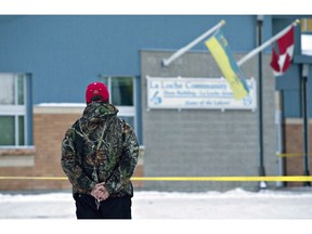 A man holds a rosary as police investigate the scene of a shooting at the community school in La Loche Sask., on Saturday, January 23, 2016. A lawyer for a young man who shot and killed four people and injured seven others in northern Saskatchewan is to argue in court today that the offender should serve his sentence as a youth.