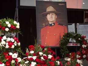 A photo of slain RCMP Constable David Wynn stands amongst flowers during his funeral procession in St. Albert, Alta., on January 26, 2015. The widow of an Edmonton RCMP officer shot and killed on duty hopes politicians take seriously any recommendations from a fatality inquiry into her husband's death. "My hopes are that anything that is recommended by the judge will be followed through with," said Shelly Wynn, whose husband Const. David Wynn was slain in 2015.