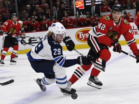 Winnipeg Jets right wing Patrik Laine (29) and Chicago Blackhawks defenseman Gustav Forsling (42) fight for the puck during the first period of an NHL hockey game Monday, April 1, 2019, in Chicago.