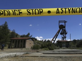 A Cypriot police officer, left, stands Monday near the flooded mineshaft where two female bodies were found. Police on the east Mediterranean island nation, along with the help of the fire service, are conducting the search Monday in the wake of last week's discovery of the bodies in the abandoned mineshaft and the disappearance of the six year-old daughter of one of the victims.