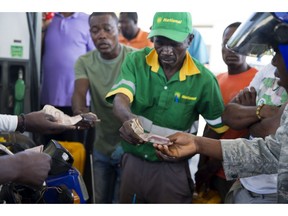 A gas station attendant collects money and gives back change during a two-week-long fuel shortage as customers buy fuel in Port-au-Prince, Haiti, Wednesday, April 10, 2019. Haiti's government, which subsidizes fuel, plans to open the gasoline market to the private sector in order to ease the shortage, according to Haiti's Director General of the Office of Monetization and Development Assistance Program Ignace Saint-Fleur, speaking to a local radio station on Monday.