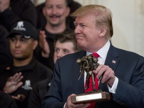 President Donald Trump holds up a statue of the Wounded Warrior Project logo presented to him during a Wounded Warrior Project Soldier Ride event in the East Room of the White House, Thursday, April 18, 2019, in Washington.