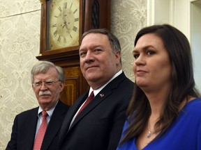 Secretary of State Mike Pompeo, center, flanked by national security adviser John Bolton, left, and White House press secretary Sarah Sanders, right, listen during the meeting between President Donald Trump and Japanese Prime Minister Shinzo Abe in the Oval Office of the White House in Washington, Friday, April 26, 2019.