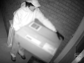 The suspect is seen at the doorway, holding a large box.