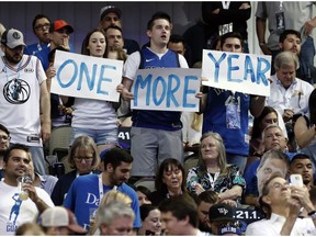 Dallas Mavericks' Dirk Nowitzki fans hold up signs reading, "One more year," during the first half of the team's NBA basketball game against the Phoenix Suns in Dallas, Tuesday, April 9, 2019. The team was playing its final home game of the season.