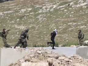 In this Thursday, Apri 18, 2019 photo, handcuffed and blindfolded Osama Hajahjeh, 16, runs away from Israeli soldiers near the village of Tekoa, West Bank. Hajahjeh said was shot in his legs last week by Israeli soldiers while he was handcuffed and blindfolded, shortly after being arrested. The military said it was investigating the incident, which it said occurred as Palestinian youths were throwing stones at Israeli soldiers.