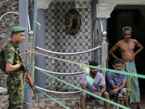 A Sri Lankan police commando secure the area of the exploded St. Anthony's Church on Easter Sunday attacks as people wait next to a small roadside in Colombo, Sri Lanka, Sunday, April 28, 2019. Sri Lanka's Catholics on Sunday awoke preparing to celebrate Mass in their homes by a televised broadcast as churches across the island shut over fears of militant attacks, a week after the Islamic State-claimed Easter suicide bombings.