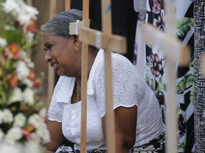 An elderly Sri Lankan woman cries sitting next to the grave of her family member who died in Easter Sunday church explosion in Katuwapitiya village in Negombo, Sri Lanka, Wednesday, April 24, 2019. Sri Lanka's president has asked for the resignations of the defense secretary and national police chief, a dramatic internal shake-up after security forces shrugged off intelligence reports warning of possible attacks before Easter bombings that killed over 350 people, the president's office said Wednesday.