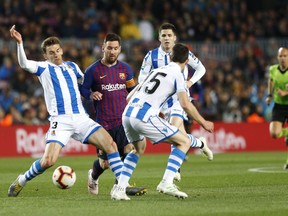 Barcelona forward Lionel Messi fights for the ball against Real Sociedad's Diego Llorente, left and Aritz Elustondo during a Spanish La Liga soccer match between FC Barcelona and Real Sociedad at the Camp Nou stadium in Barcelona, Spain, Saturday, April 20, 2019.