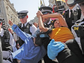 Police arrest a protestor couple who are glued together by their hands, at Oxford Circus in London, Friday, April 19, 2019. The group Extinction Rebellion is calling for a week of civil disobedience against what it says is the failure to tackle the causes of climate change.